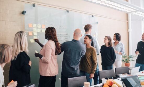 Group of people collaborating using post-it notes on board
