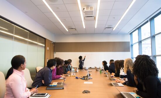Group of women on laptops in a boardroom meeting