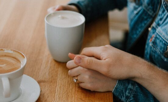 Two hands locked together while drinking coffee