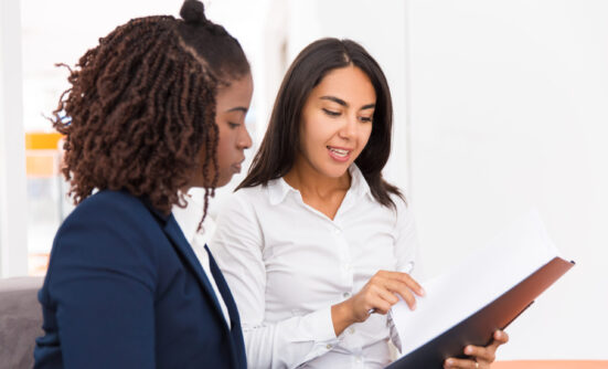 Two women discussing paperwork