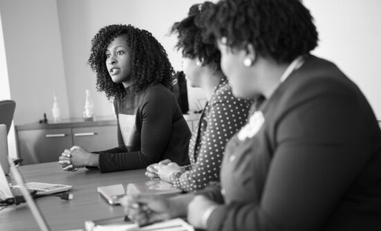 Three women sitting on a table discussing something