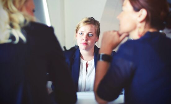Woman in suit sitting in front of two women talking